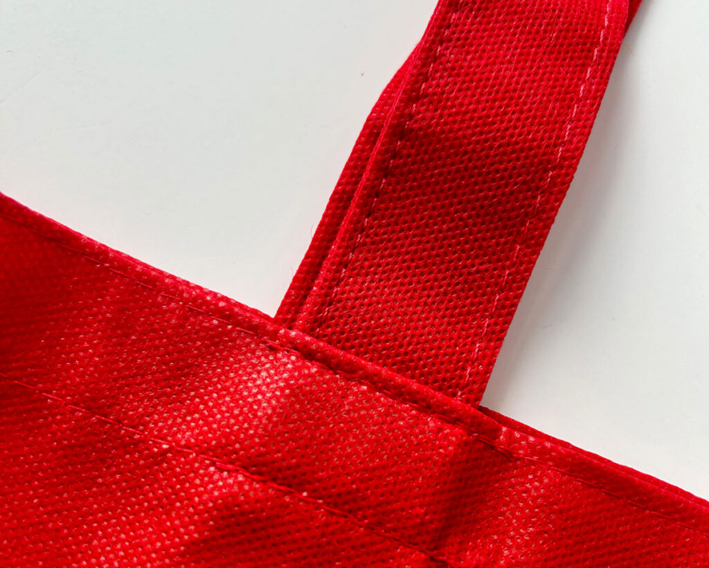 Detalhe da costura em nossas sacolas de TNT personalizada da Copy House, mostrando a resistência e durabilidade do acabamento, ideal para empresas que buscam brindes corporativos de qualidade.