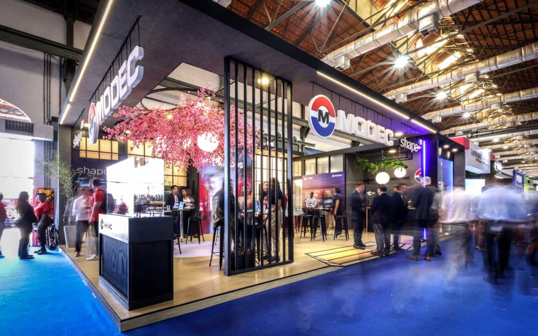 MODEC exhibition booth at Rio Oil & Gas 2024 in Rio de Janeiro, featuring modern signage, displays, and large-format printed visuals. Copy House offers professional printing, logistics, and bilingual support for international exhibitors.
